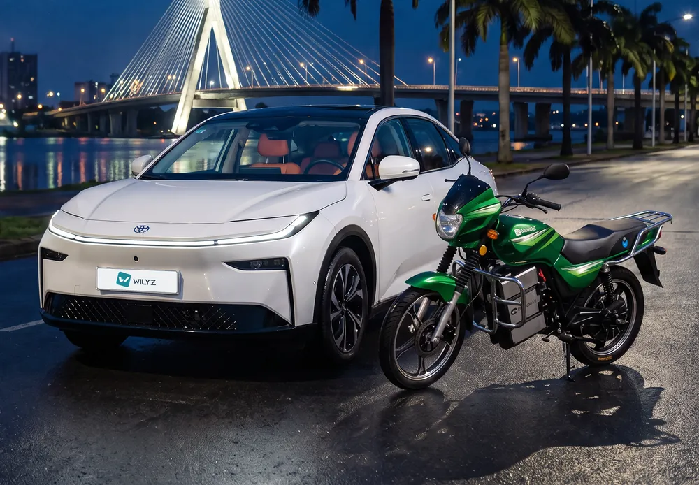 La Toyota bZ3X blanche et la moto électrique Wilyz au bord de la lagune Ébrié à Abidjan, de nuit, devant le pont à haubans Alassane Ouattara éclairé